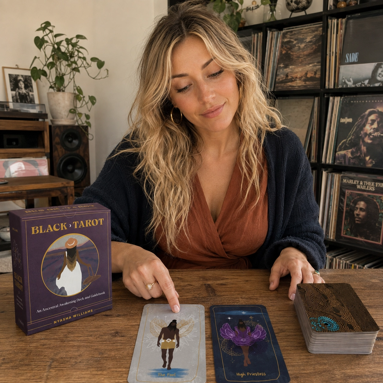 Aurica reading Black Tarot beside its box, The Fool, High Priestess, and the stacked deck