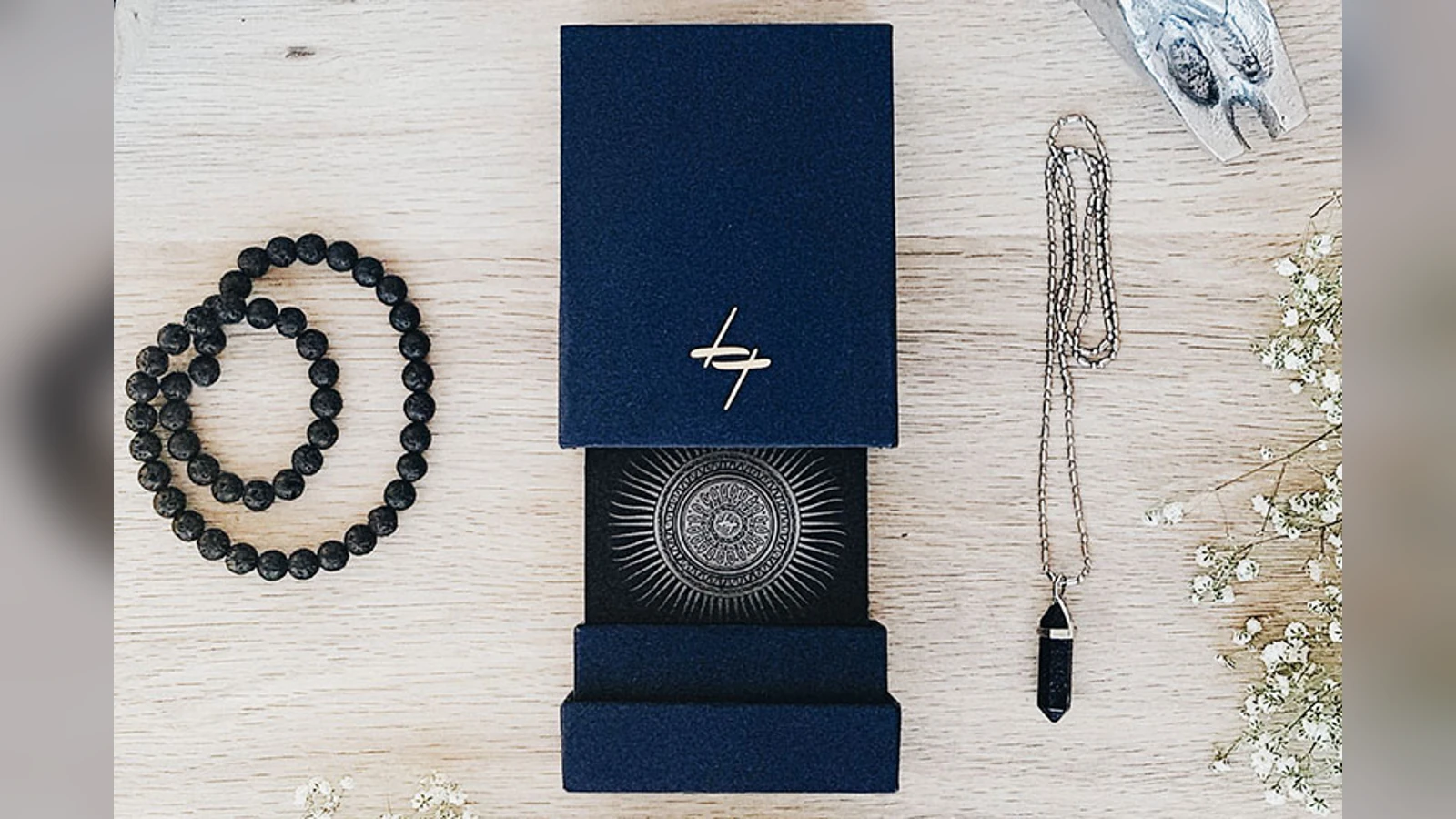 Official Lotus Tarot Signature Deck box, card back, beads, and pendant arranged on pale wood