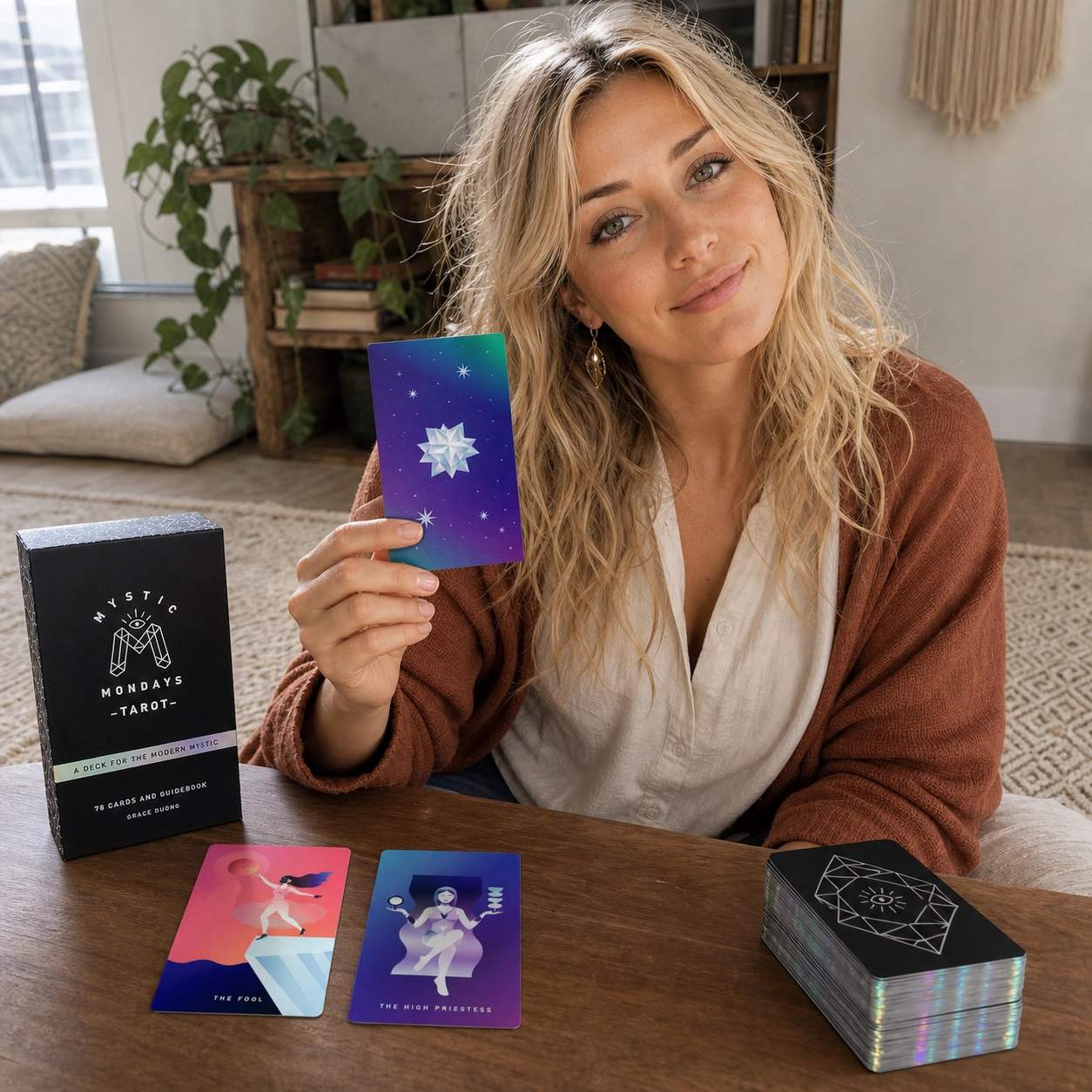 Aurica holding The Star while reading Mystic Mondays Tarot beside its box, face-up spread, and stacked deck