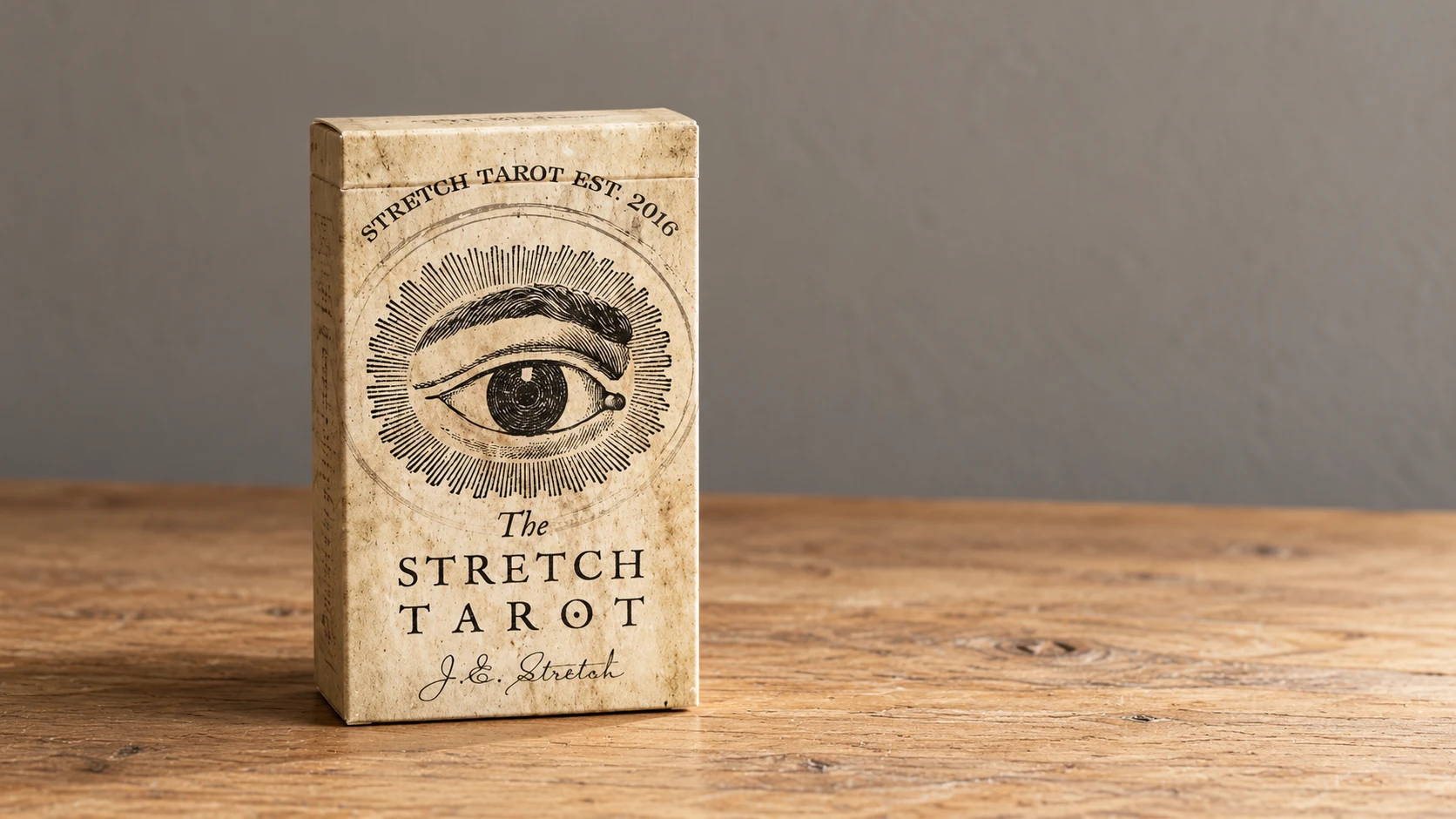 AI-generated editorial scene of the Stretch Tarot Deck by Joseph Stretch: one closed parchment-eye box on a bare wooden table against a plain neutral wall