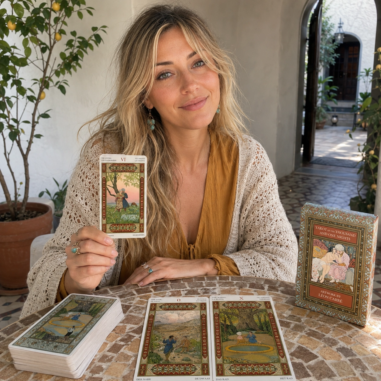 Aurica presenting The Lovers from Tarot of the Thousand and One Nights beside The Fool, The Wheel, the deck box, and the stacked deck